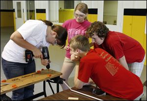 Clockwise from left, Katelyn Schiefer assembles a portion of the aircraft as Sarah Walas, Philip Streacker, and Rodney Park observe. The aircraft will be used as a chase plane for a re-enactment of the first transcontinental flight in 1911 by the Vin Fiz.