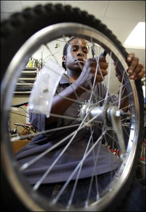 Volunteer William Rowlett removes a tire from a rim to be repaired.