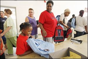 Slug: REL BACKPACKS20p          Date 8/20/2009           The Blade/ Amy E. Voigt           Location: Toledo, Ohio  CAPTION:  Kennedy Gibson-Harrison, left, reacts to her new backpack and school supplies while her mother Shelly Taylor (cq), rightfrom Toledo, ushers her through the line at The Salvation Army on August 20, 2009.