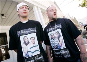 Brothers Gerald, left, and Raymond Smith, don T-shirts in memory of their slain sister, Jennifer Shively, during yesterday's news conference at the home of Esther Swope, the victim's mother.