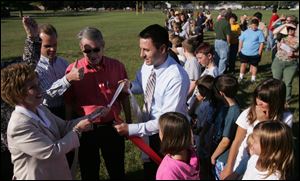 From left: Julie Everly, co-principal of Hollywood Elementary in Monroe, superintendent David Taylor, school board president Robert Yeo, and co-principal Ryan Starr take part in a knot tying that symbolically connects Cantrick and Hollywood schools. Ribbon was stretched from the front doors of each school to symbolize the unity of the two schools. 