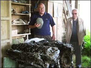 Members of the Normandy Association for Air Remembrance, which was founded in 1994, look over the remains of a plane's engine.