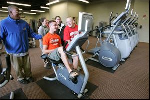 From left, Start High School band members Kingsley Eigbire, Melissa Millward, Dan Avery, Christina Notario, and Ben Baer check out the equipment in what used to be their band room. Annette Coates and her daughter, Angel Shedd, examine the weight room at the new YMCA.