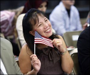 Lovelace Arnobit Ambucay proudly displays the American flag she was given after becoming a U.S. citizen Thursday during naturalization ceremonies at McCord Junior High School in Sylvania.