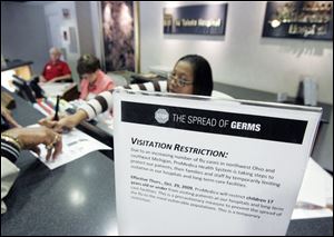 A sign at the entrance of Toledo Hospital warns visitors of a new policy that restricts visits by children under age 17 at ProMedica hospitals and long-term care facilities in the region.
