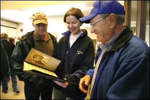 Rick Barricklow, left, and hs wife, Kati, join Morgan Ford of the Burnham High School class of 1938 to review class pictures during an open house held before the building is demolished. 