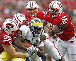 Michigan's Floyd Simmons is stopped by Wisconsin's Patrick Butrym (95) and O'Brien Schofield (50) in yesterday's game. The Badgers are 8-2, 5-2 in the Big Ten.