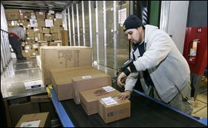 Daniel Campos scans packages before they are loaded into trucks at the FedEx hub in Perrysburg Township. FedEx and UPS say the demand for shipping has picked up this holiday season.