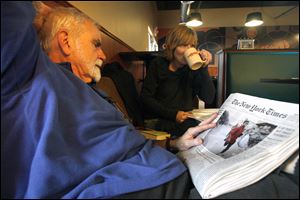 Frank Ayers of Toledo scans a newspaper for details of the crisis in Haiti while Toledoan Heather Meyer listens to a performance during a fund-raiser for  relief efforts for survivors of last week's earthquake in Haiti. Yesterday's event at Caffeini's Coffee, 1471 Secor Rd., included music, poetry readings, and lectures. In addition to donations, Caffeini's contributed part of its proceeds to the Red Cross. Elsewhere, Prestige Restaurant, 3439 Hill Ave., says it will donate a portion of all proceeds from 9 a.m. to 8 p.m. today to the American Red Cross for Haitian relief.
