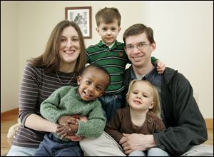 Rachel and Keith Simpson pose in their home in Holland with their children, David, 20 months, who was adopted from Ethiopia; Henry, 4, and Ruth, 3.