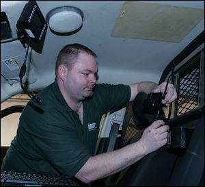 Dennis Ebel works on installing the new system in a city police cruiser. Police officials especially like the backseat camera and recorder, which can capture evidence that suspects might divulge. Installation is expected to be finished by the end of the month.
