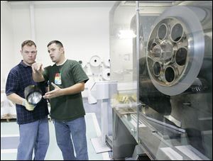 Tom Cope, left, and Pat McCloy discuss a job at Uni-Solar in Auburn Hills, Mich., which produces photovoltaic roofi ng material. Michigan offers tax credits targeted toward solar-equipment manufacturers. Uni-Solar operates several plants in the state.