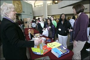 Mary Plews, left, of the Toledo-Lucas County Public Library shares college information with Maya Mitchell, 12, and Sherice Whyte, 12. Washington Local counselor Sara Hoffman is at right.