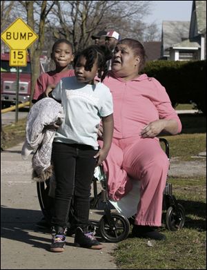 Shirley Tabb and grandchildren Destine and Dezier Tabb watch as crews spray her home next to the one that burned. No one was hurt in the blaze yesterday afternoon.