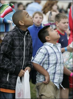 Julian Hill, 9, at left, keeps his eyes on the sky on a blustery day outside the Church on Strayer in Monclova Township.