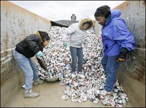 Slug: CTY earthday17p A The Blade/Jeremy Wadsworth    Date: 04/17/10  Caption: Left to right Atazhe Herron, 10, Nakita Thompson, 10, and Norla Long of Aluminum Cans for Burned Children of Northwest Ohio smash cans collected Saturday, 04/17/10, at the Toledo Zoo during Earth Day festivities.