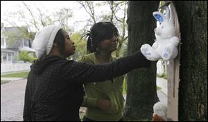 Tiffany Smith, left, and Marsia Hampton visit a memorial to Darrin Smith near the location on Grand Avenue where he was shot and killed during an argument Saturday night.