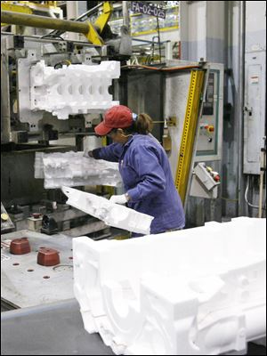 Defiance employee Pearl Reyna inserts halves of foam engine-casting forms into a machine that glues them together. 
