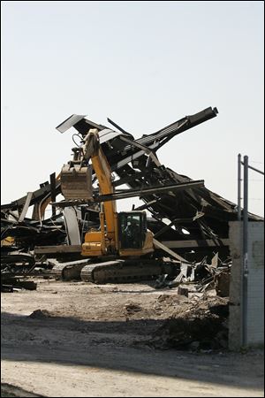 Employees of Burge Wrecking LLC move some of the debris that will be cut up and recycled from the 90-foot-high structure they razed Monday afternoon.