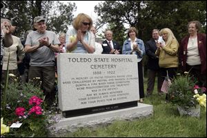 Jane Weber, a member of the Toledo State Hospital Cemetery Reclamation Project, looks at the monument at the dedication. More than 140 people attended.