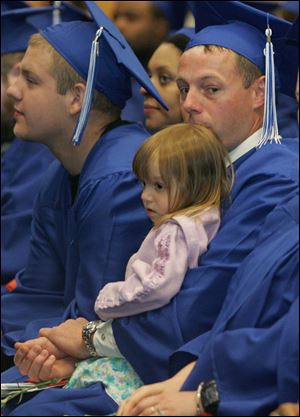 Franklin Blackwood holds his daughter Ava at the GED ceremony. Having grown up with the dream of becoming a police officer, he now is studying criminal justice as Owens.