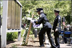 Officer Katrina Welch-Bills of the Toledo Police Department's honor guard places a wreath at the Toledo Police Memorial Garden to honor colleagues who have died in the line of duty. Behind her is Chief Mike Navarre. 