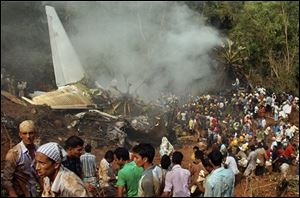 Civilians look on as Indian firefighters and rescue personnel gather around the site of an Air India plane that crashed in Mangalore, in the southern Indian state of Karnataka, Saturday, May 22, 2010. The Air India Express plane trying to land in the rain at a tricky hilltop airport in southern India overshot the runway, crashed and burst into flames at dawn Saturday, killing nearly 160 people, officials said. At least eight survived.