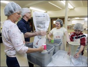 From left, Joy Hodak, Rick Ellis, Theresa Buehler, and Derek Huddleston pack meals in assembly-line fashion at St. Paul Lutheran Church in Maumee as part of the Kids Against Hunger project. The members' goal was to assemble 30,000 food packages to be shipped to Haiti.