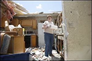 Shirley White sorts through belongings in her destroyed home. She clung to a bathroom sink as the storm tore the house apart.