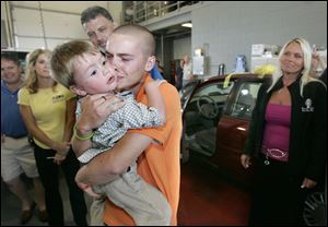 Beth and Mike Cousino, background, and Stephanie Tinney, right, watch Gerald Lathrop hug his son, Gerald Lathrop, Jr., 2, in the Lake Township fire station.
