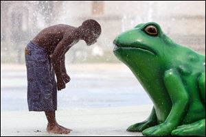 Lamon Witcher, 9, of Toledo cools off in a misty stream from the water frog at the splash pad at Savage Park in Toledo, which also opened Monday.