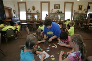 Amid a room full of youths making portions of quilts, Betty Metz of Oregon helps Sidney Carlen, 9, of Oregon with needlework. Others, clockwise from Ms. Metz, are Scarlet Rice, 9; Faith Schweizer, 9, and Madison Rice, 10, all of Oregon.