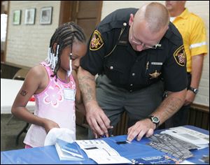 Lucas County Sheriff's Deputy Richard Veitch, Jr., fingerprints Quianna Ballard, 8.