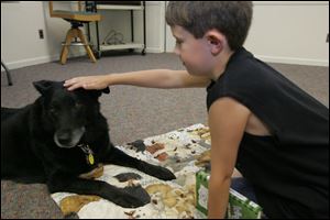 Noah Waszak of Toledo rewards Lucky with a pat on the head for listening to him read 'Diary of a Wimpy Kid: The Last Straw' in the Paws to Read program.