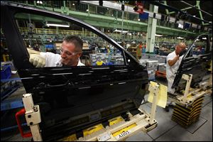 A worker installs fittings on doors at the Marysville, Ohio, factory, where too different models can be produced side by side on the same assembly line.
