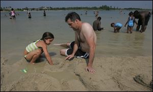Mitch Crawford, a teacher on summer break from St. John's High School, plays in the sand Monday with his daughter Addison, 6, at Maumee Bay State Park.. 