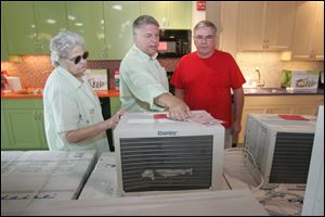 Chuck North, center, shows an air conditioner to Dolores Holdran and her son Jim Fry at the Appliance Center in Maumee, where demand for large window units has been strong.