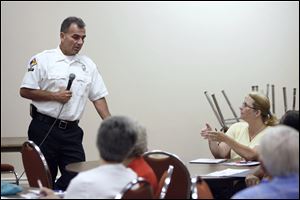 Capt. Rick Syroka listens to a question from Jenny Meyer of Toledo during a meeting downtown between Block Watch leaders and fire officials to talk about the city's arson epidemic.