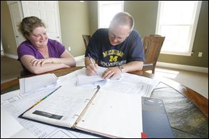 Beth and Scott Swartz go over plans for their new home in Millbury. A ranch house will take the place of their two-story home that was ripped away by a tornado on June 5.