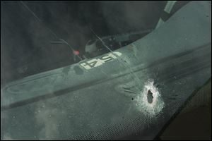 The windshield of Officer George Shaughnessy's police cruiser has a hole from one of several bullets fired at it in South Toledo.