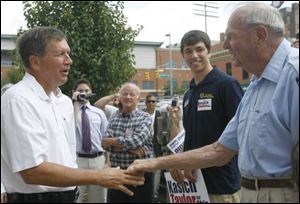John Kasich, left, shakes hands with Peter Petersen of Toledo in front of the Lucas County GOP headquarters downtown.