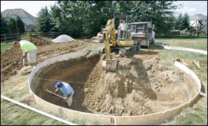 A crew from Hawaiian Pool Builders in Maumee works on a residential pool in Maumee. Company president Mike Kerr says residential pool sales are up 50 percent overall from last year. 
