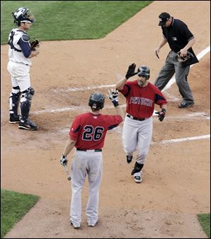 Pawtucket's Mike Lowell is greeted by Lars Anderson at home plate after hitting one of his three home runs at Fifth Third Field, a record for a visiting player, as Hens catcher Max St-Pierre watches. 
