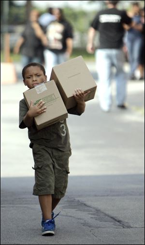 Seth Ward, 7, of Toledo carries boxes from Feed The Children, which distributed food and toiletries at the Erie Street Market.