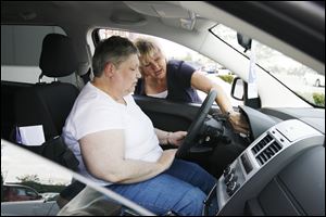 Joan McVicker listens intently as Charlie's Dodge sales representative Carol Gerken leans in to explain some of the features of the Dodge Journey in Maumee.