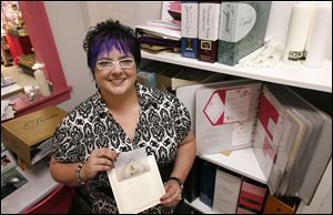 Kelly Heuss, owner of Puttin' on the Glitz inPerrysburg, displays a wedding invitation.