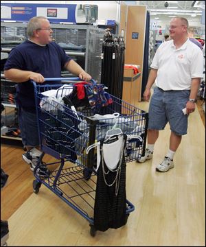 Duane Lender of Millbury, left, stops and chats with his neighbor Scott Swartz while shopping at Meijer in Maumee with gift cards provided for storm victims by area Lions Clubs. The Lender and Swartz families lost their homes in the June 5 tornado.