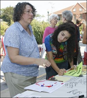 Beverly Elwazani, left, and her daughter Layan Elwazani, 16, both of Bowling Green, sign up to volunteer to help in the effort to pass the levy for the Wood County District Public Library at Monday's rally.
