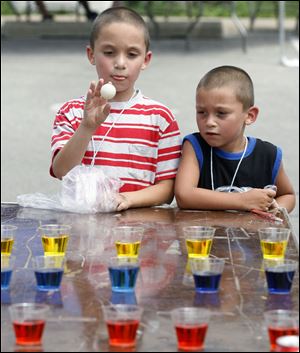David Arce, 5, watches as his brother Daniel Arce, 7, plays a game that challenges him to toss a Ping-Pong ball into a cup.