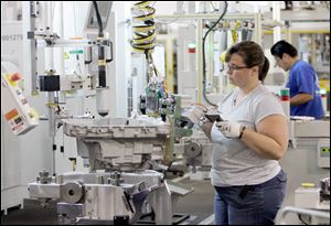 Quality inspector Rhonda Modrzynski prepares a transmission case for assembly at GM's Toledo Powertrain, where improvements in ergonomics have decreased injuries and further increased efficiency at a factory consistently honored for its productivity. 